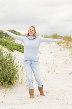 女人站在沙滩上张开双臂