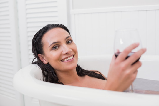 躺在浴缸里拿着一杯红酒的女人