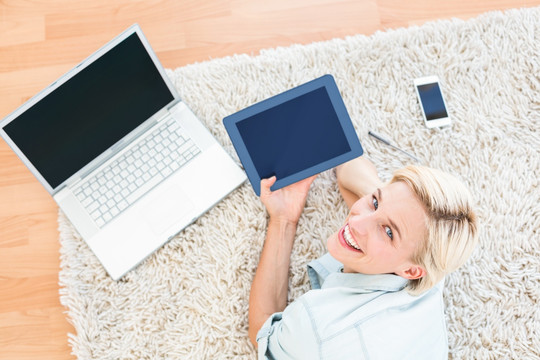 趴在地毯上使用平板电脑的女人