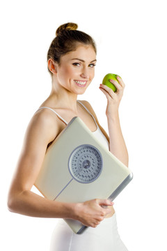 拿着一个苹果和体重秤的女人