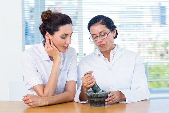 看着导师捣碎罗勒植物的女科学家