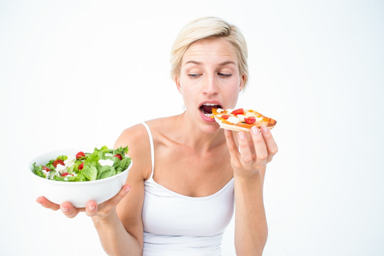 吃披萨的女人看着一盘沙拉