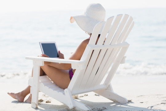 坐在沙滩椅上使用平板电脑的女人