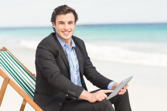 坐在沙滩椅上用平板电脑的男人