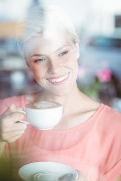 微笑的女人在喝一杯咖啡