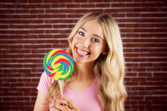 微笑的女人拿着一根彩色棒棒糖