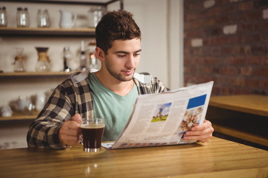 在咖啡馆里边看书边看报纸的男人