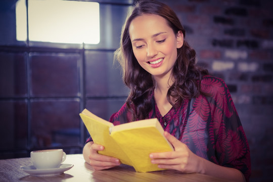 微笑的女人在咖啡馆里看书