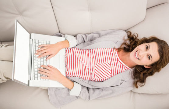 躺在沙发上使用笔记本电脑的女人