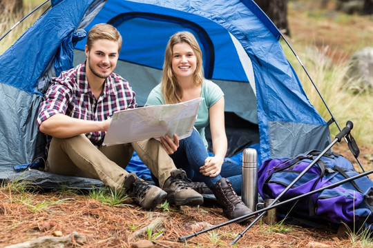 坐在帐篷里看地图的夫妇