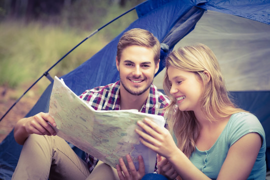 坐在帐篷里阅读地图的夫妇