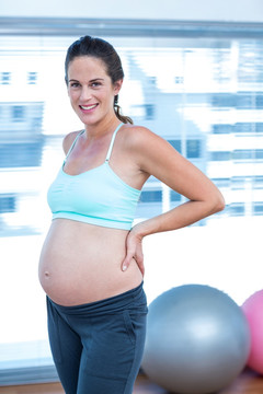 微笑的孕妇站在健身房里