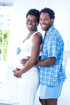 微笑的男人拥抱着怀孕的女人