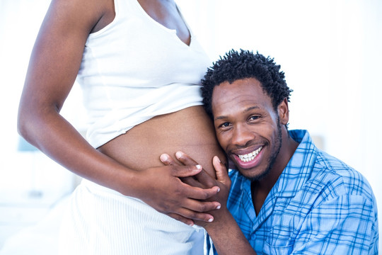男人微笑着摸着怀孕妻子的肚子