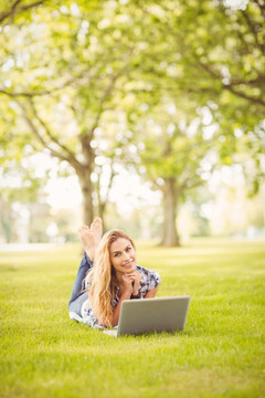 趴在草坪上用笔记本电脑的女人