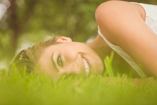 微笑的女人躺在公园草地上