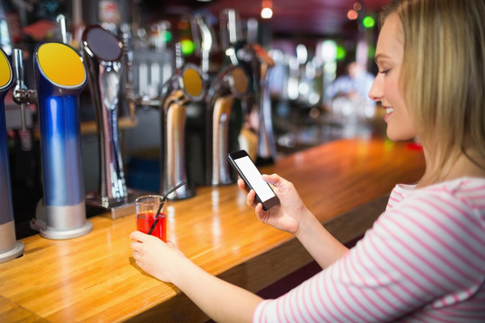 在酒吧使用手机的商务女人