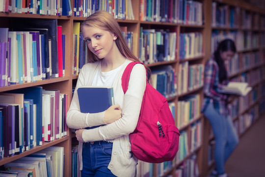 抱着书本的女大学生在图书馆里