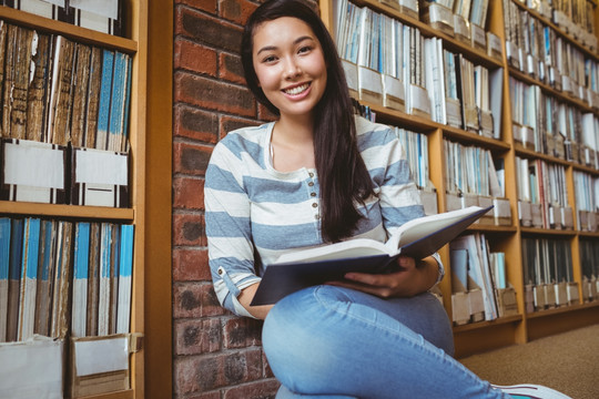 坐在图书馆里地板上看书的女学生