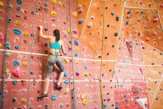 在健身房里爬攀岩的年轻女人