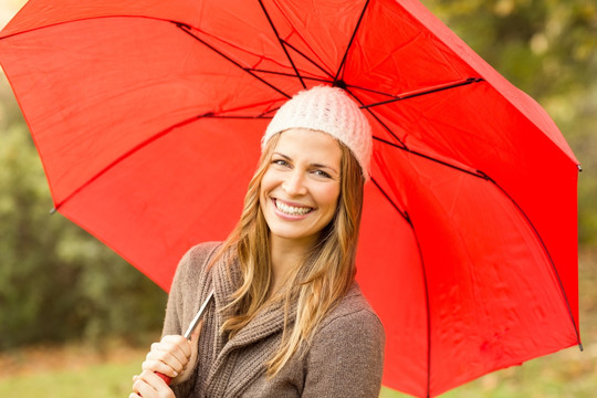 微笑的年轻女子撑着一把红伞