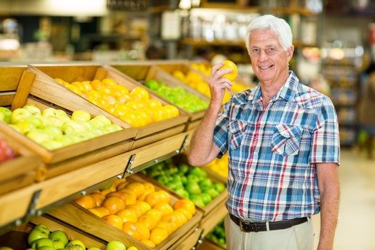 微笑的老人拿着苹果在超市里
