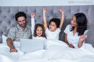 坐在床上使用笔记本电脑的家人