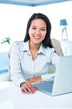 微笑着使用笔记本电脑的商务女人