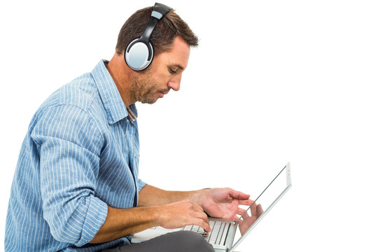 戴着耳机使用笔记本电脑的男人