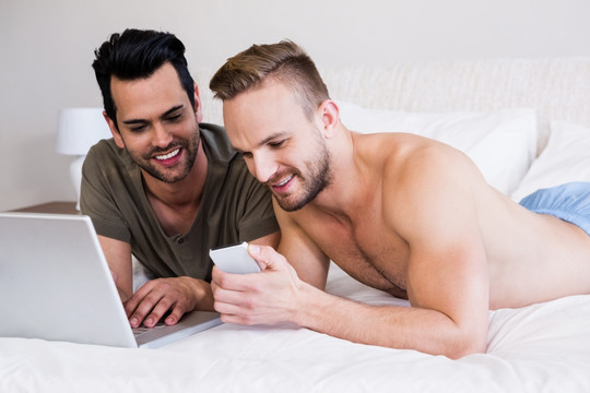趴在床上使用手机的两个男人