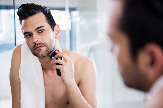 英俊的男人在浴室里刮胡子