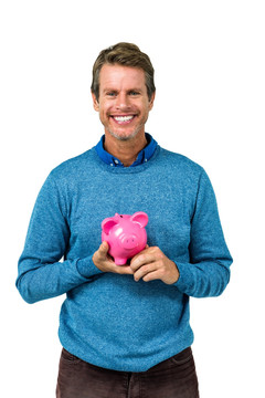 微笑的男人拿着一个小猪储钱罐
