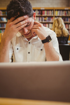 疲惫的男学生在图书馆里学习