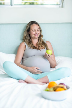 怀孕的女人在她的卧室里拿着苹果