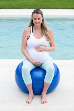 微笑的孕妇坐在健身球上