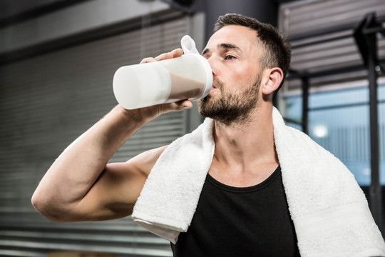 在健身房里喝蛋白粉的男人