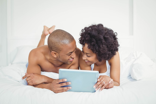 在床上使用平板电脑的快乐夫妇
