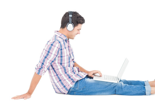 戴着耳机的男子坐在地板上用电脑