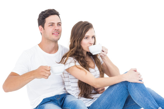 年轻夫妇坐在地板上喝咖啡