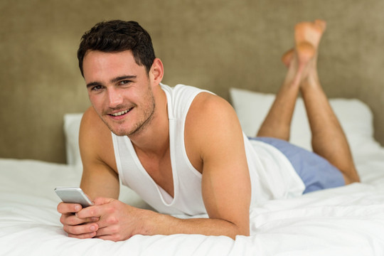 趴在床上使用手机的男人
