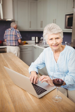 在厨房里使用笔记电脑的老夫妇