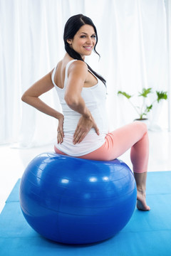 坐在瑜伽球上锻炼的孕妇