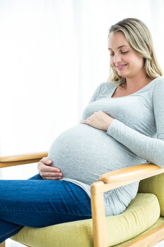 坐在椅子上看着肚子的孕妇