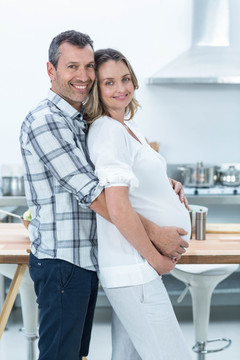 男人微笑着拥抱怀孕的妻子