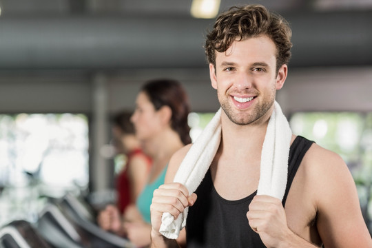 微笑的男人在健身房里拿着白毛巾
