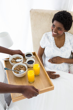 孕妇微笑着看着男人拿来的早餐
