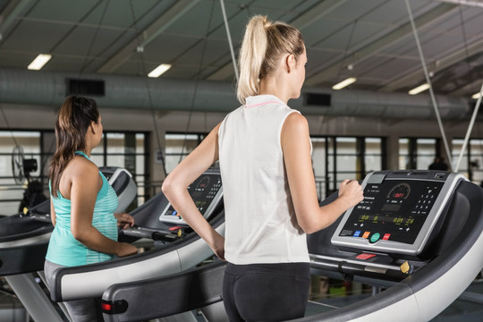 在健身房里使用跑步机的两个女人
