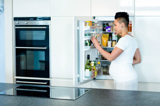 在冰箱里找食物的孕妇