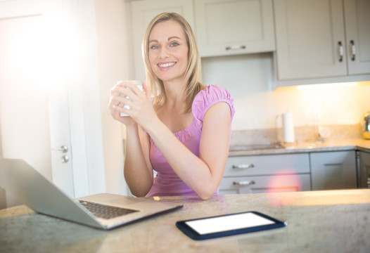在家里喝咖啡用笔记本电脑的女人
