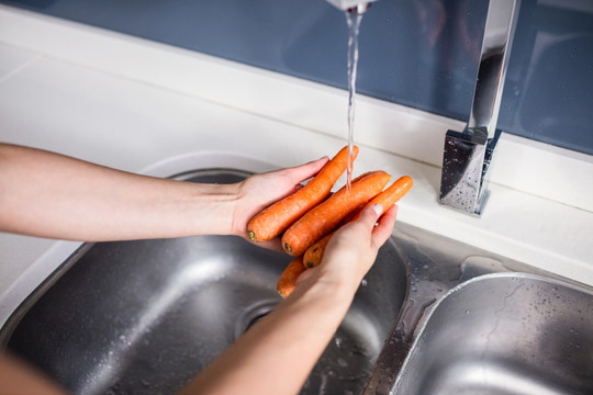 女人在厨房的水槽里洗胡萝卜